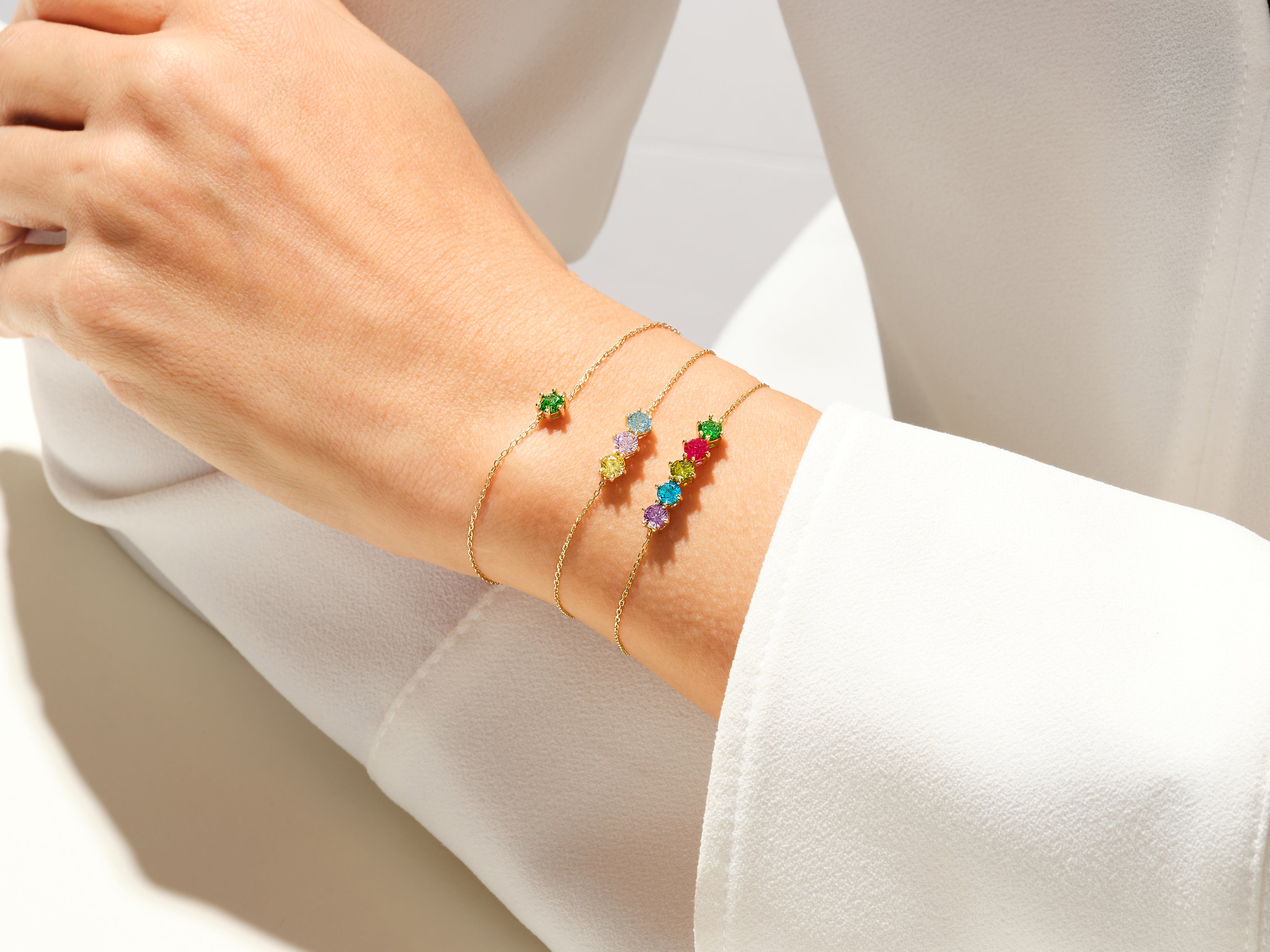 Gold bracelets with colorful gemstones on a woman's wrist