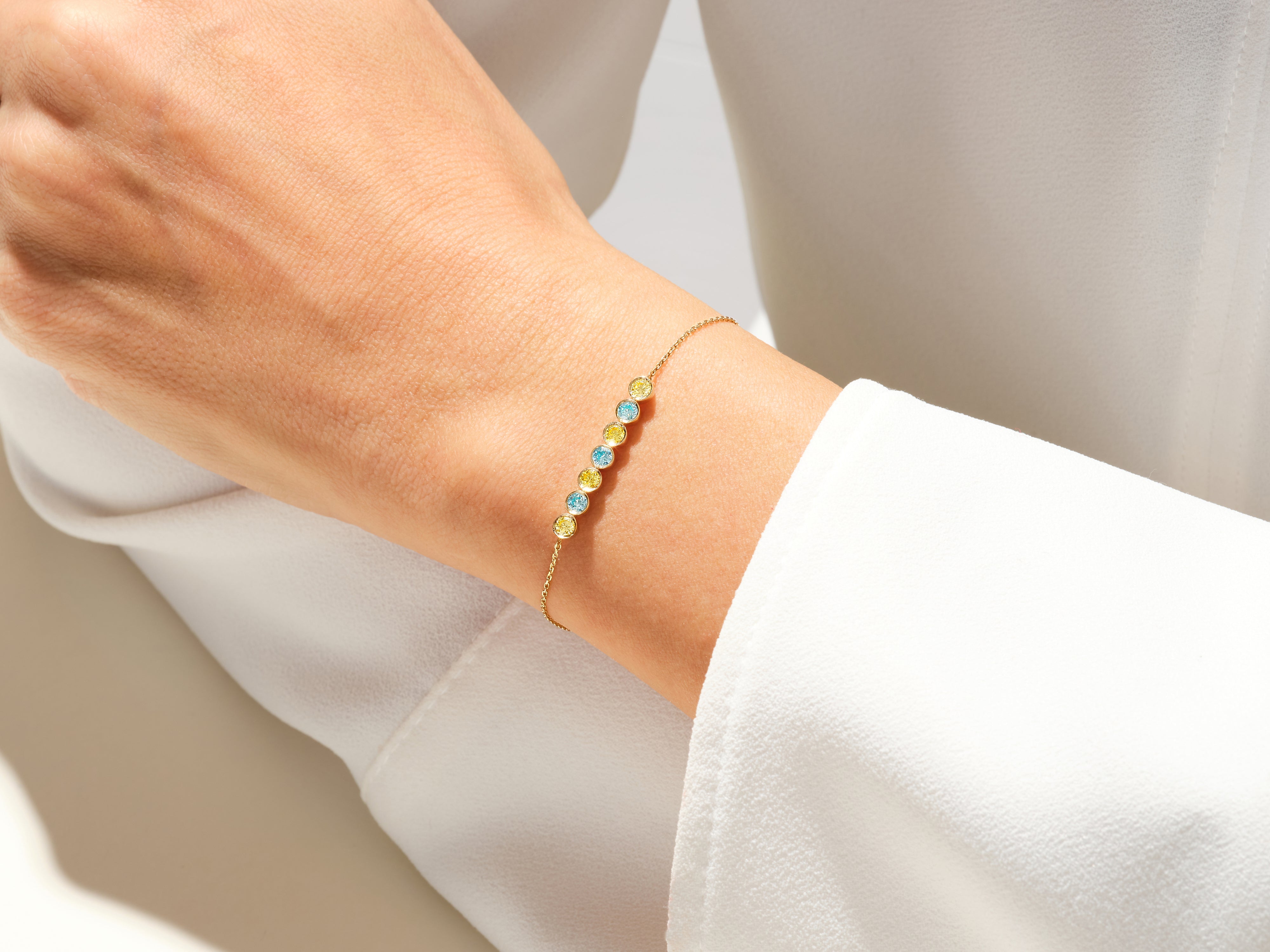 Gold bracelet with blue and yellow gemstones on a woman's wrist