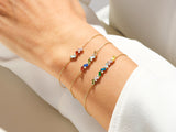 Gold chain bracelets with colorful gemstones and diamonds on a wrist