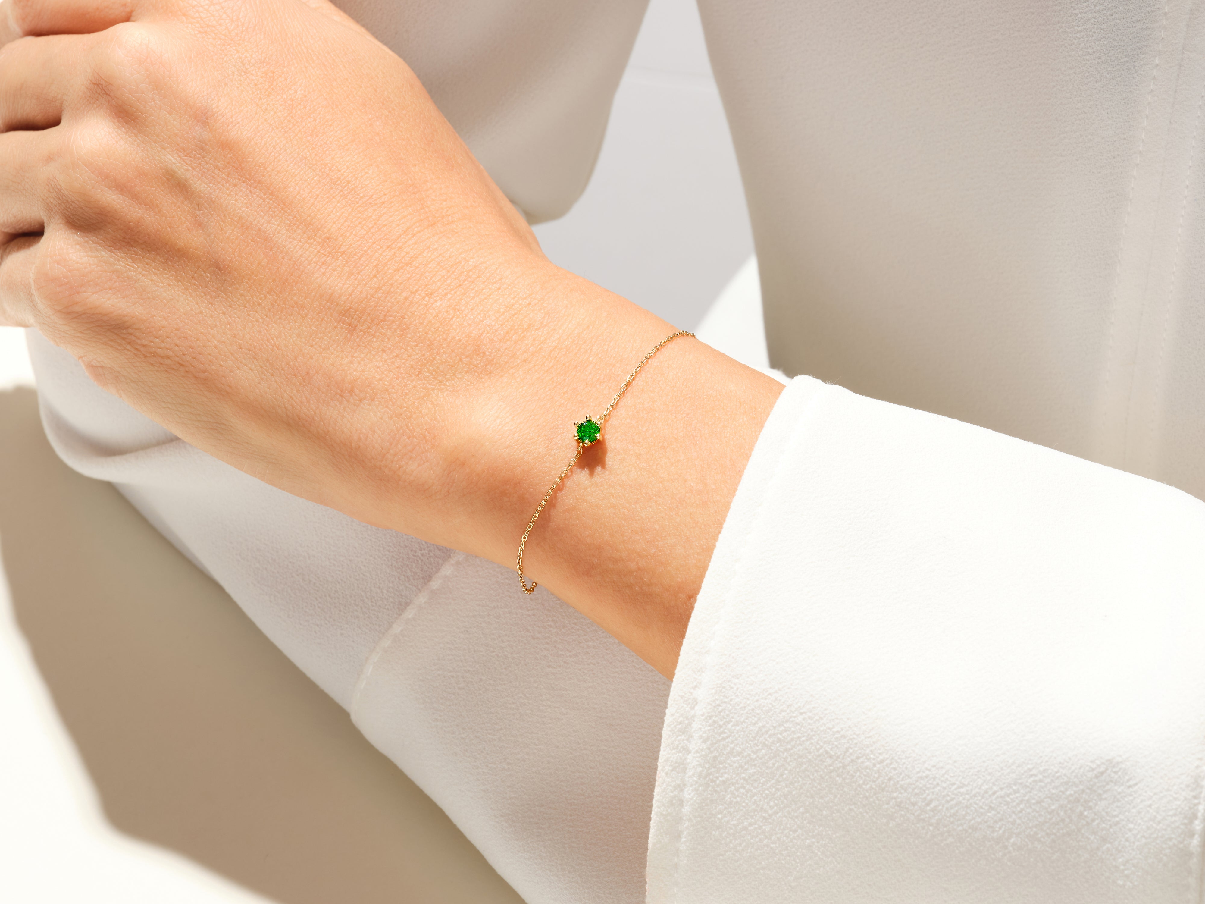 Gold chain bracelet with a single green emerald gemstone