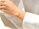 Gold chain bracelet with single red gemstone on wrist
