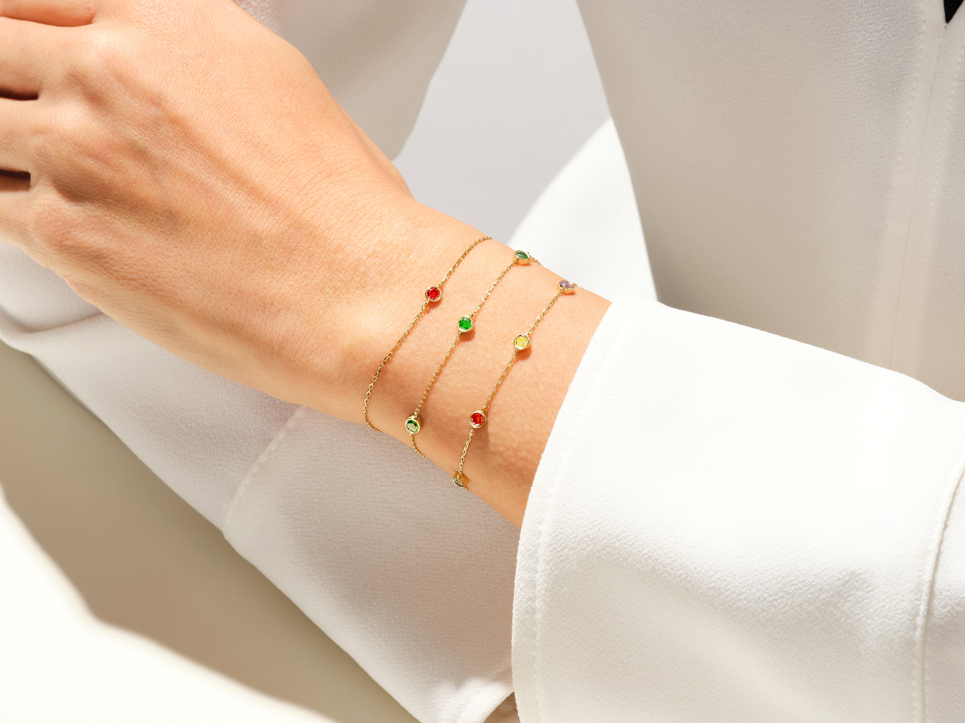 Gold bracelets with colorful gemstones on a woman's wrist