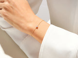 Delicate gold bracelet with a single pink gemstone on a woman's wrist