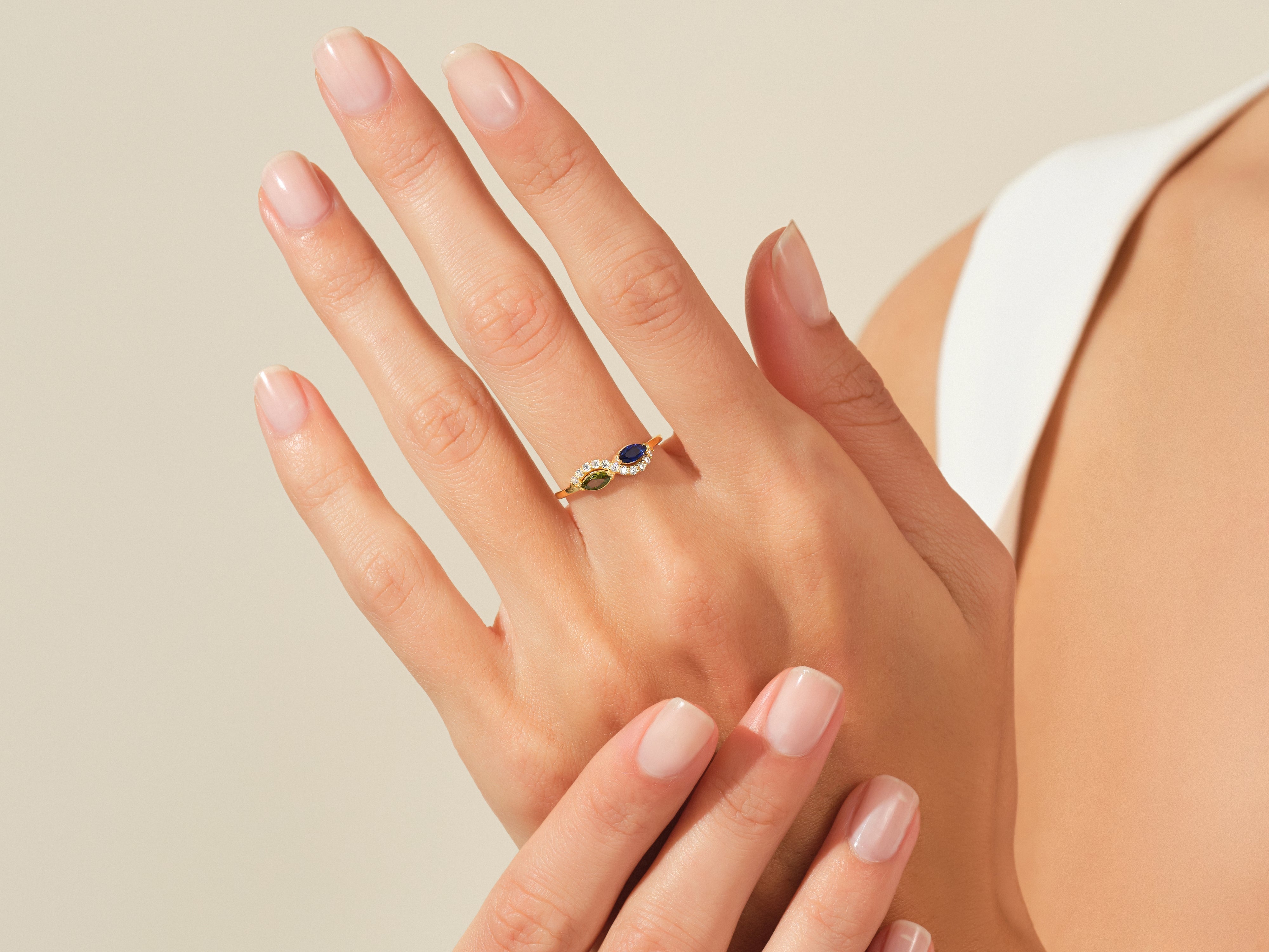 Gold ring with blue and green gemstones on a woman's hand