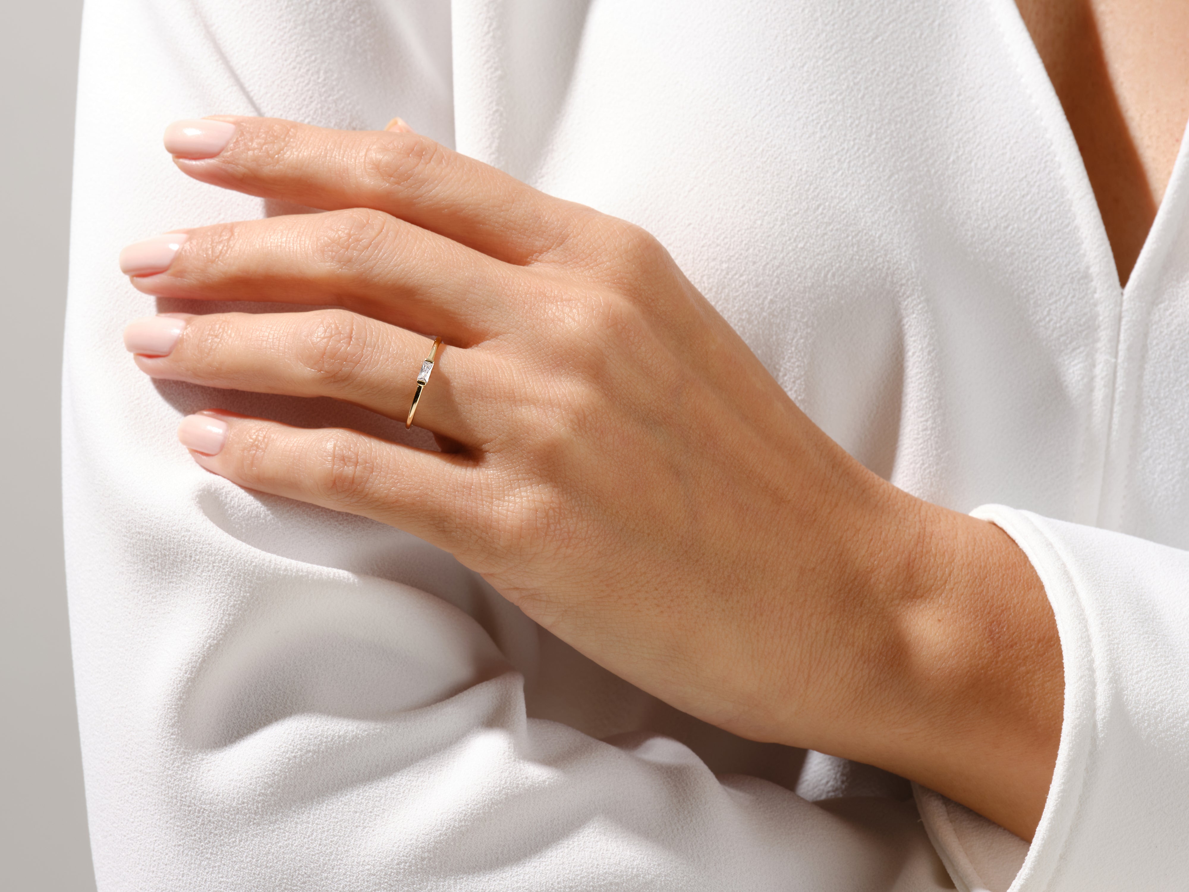 Delicate gold ring with baguette diamond on elegant hand