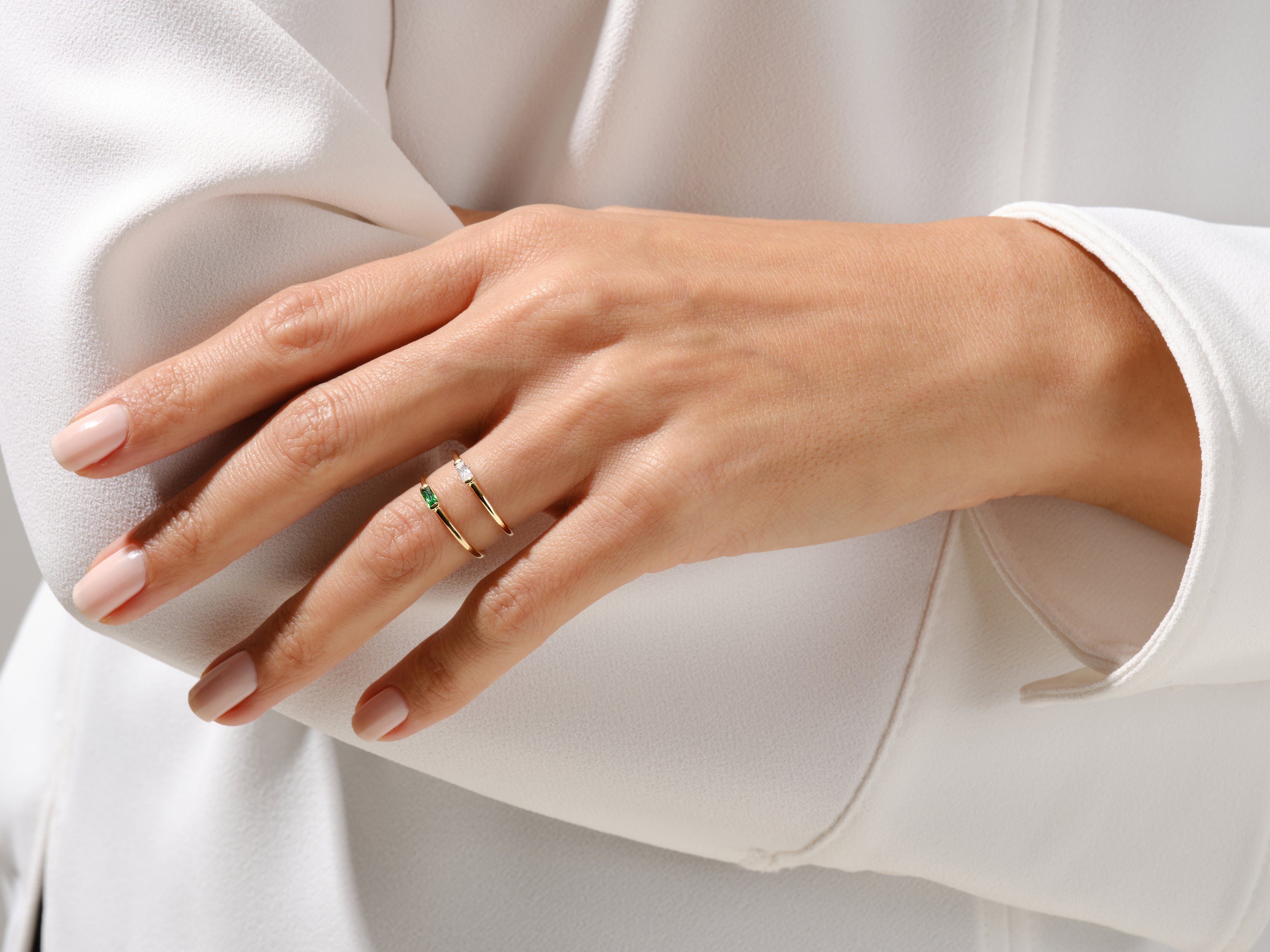 Elegant gold rings with emerald and diamond gemstones on a hand