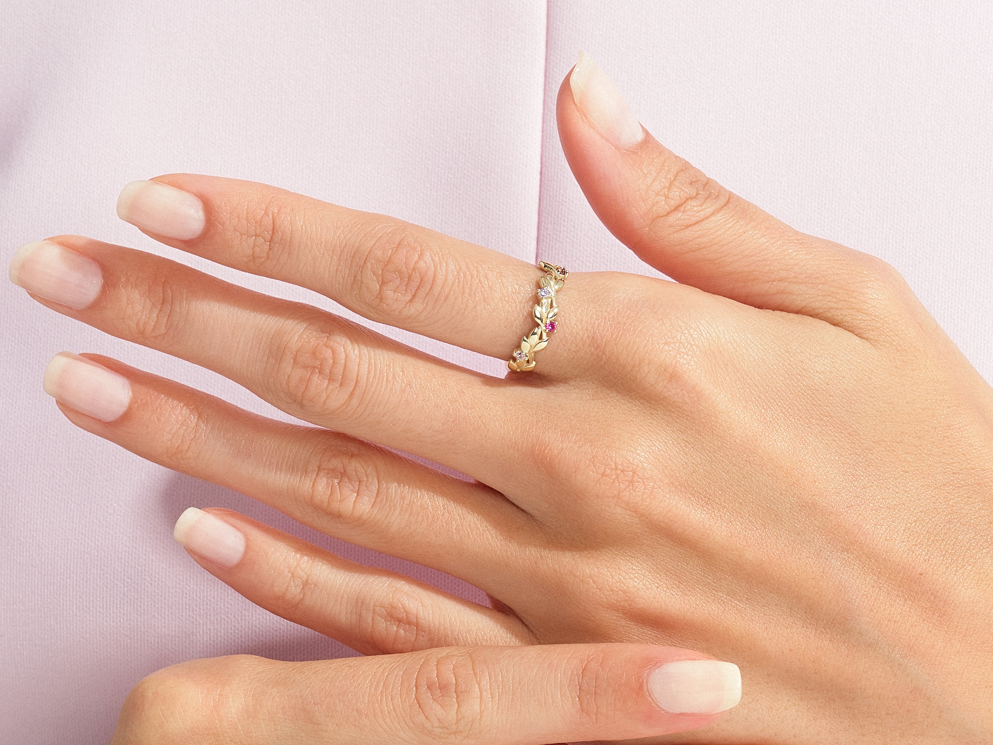 Gold leaf ring with pink and clear gemstones on a hand