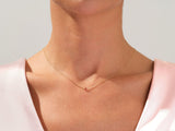 Delicate gold necklace with a single ruby gemstone on a woman's neck