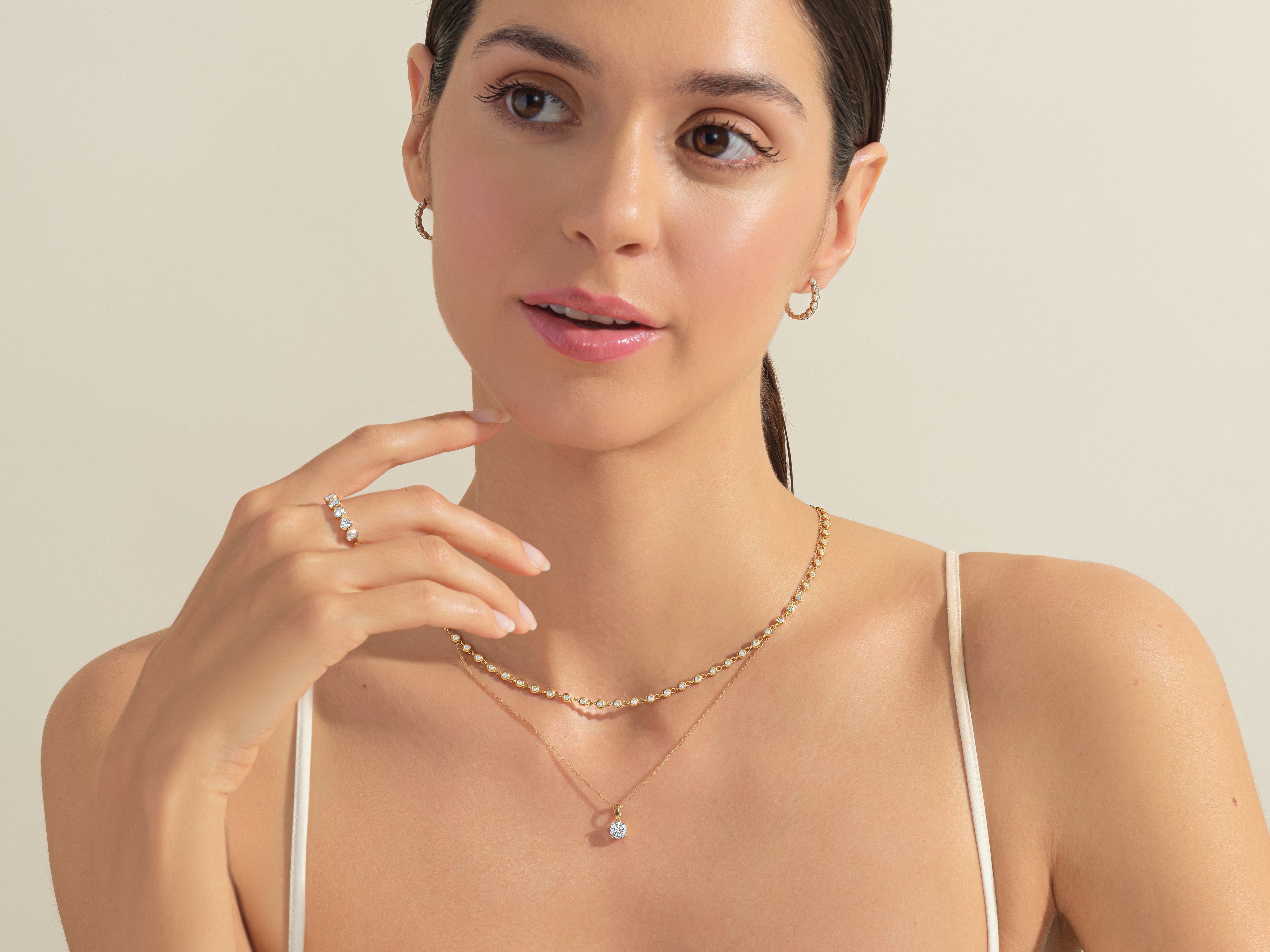Woman wearing diamond necklace, ring, and earrings, showcasing fine jewelry